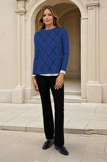 Woman wearing a blue sweater and black pants standing in front of a classical building.