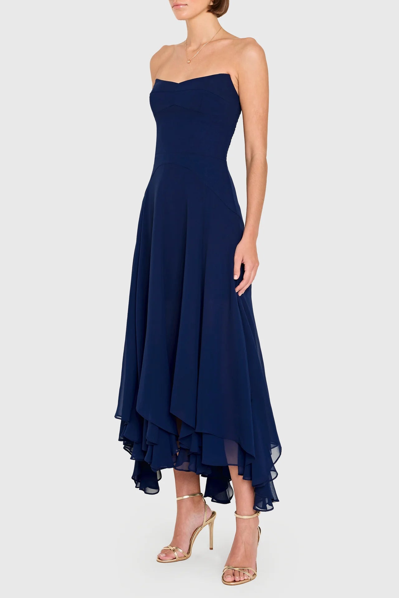 Navy strapless dress with an asymmetrical hem on a white background