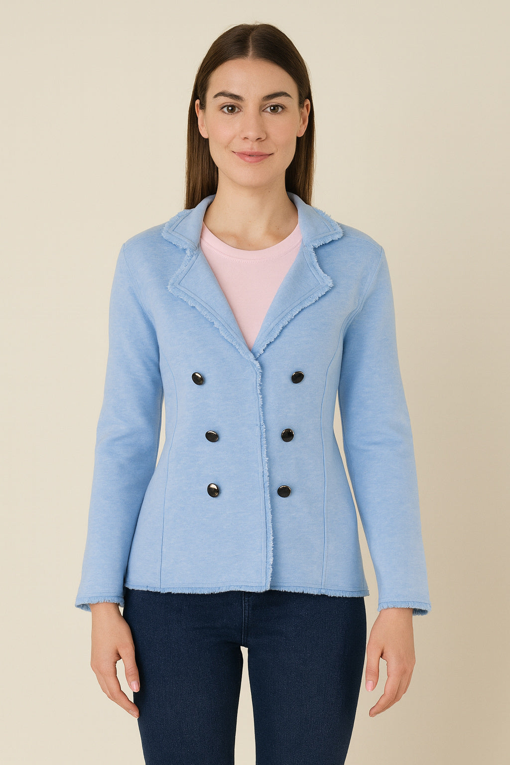 Woman wearing a light blue jacket with black buttons on a beige background