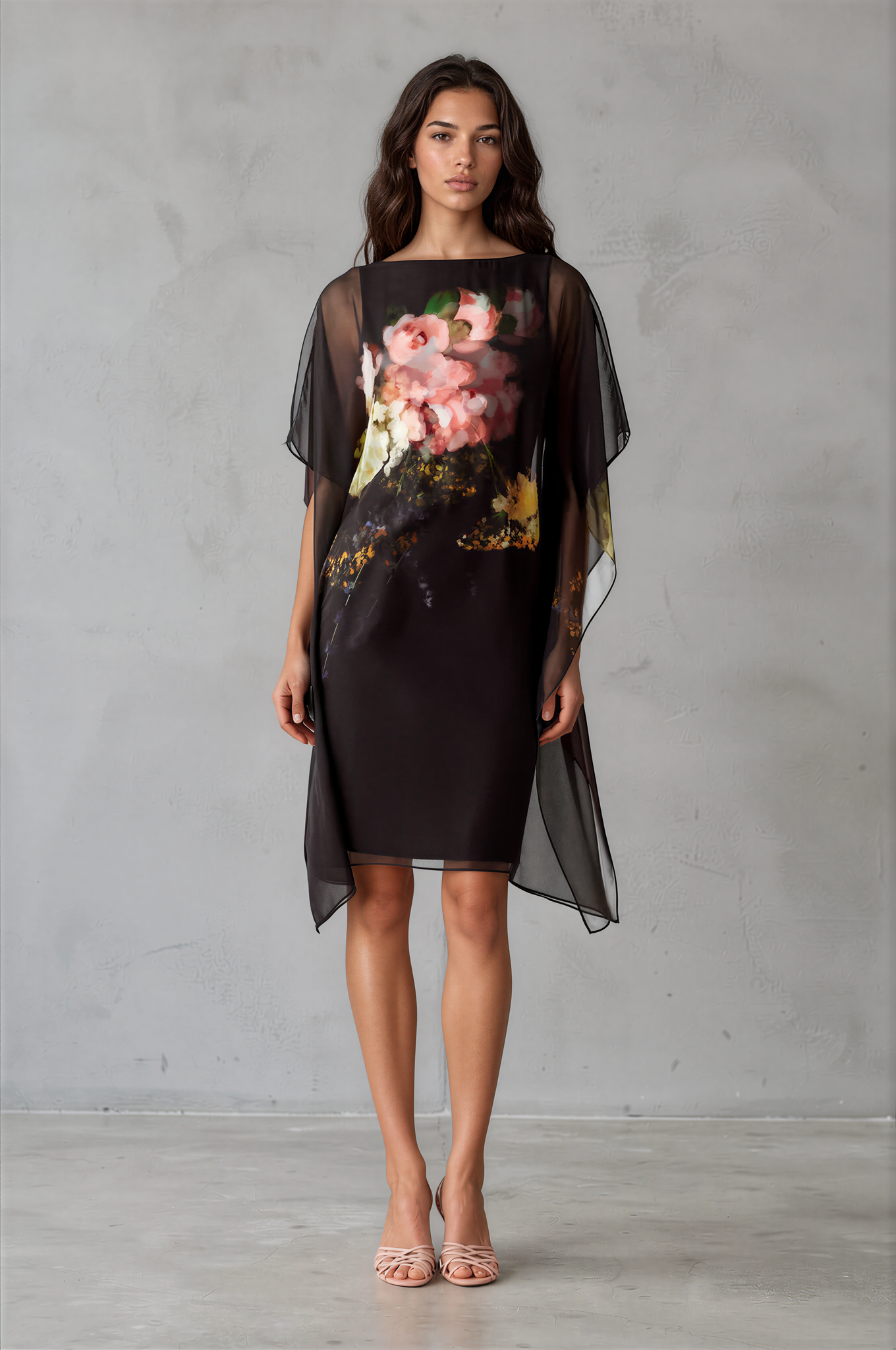 Woman models a black sheer overlay dress with a large pink and white floral print on the front by Teri Jon Chiffon Print Caftan Overlay Dress