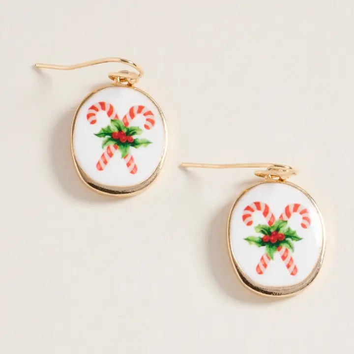 Pair of earrings with candy cane and holly design on a beige background