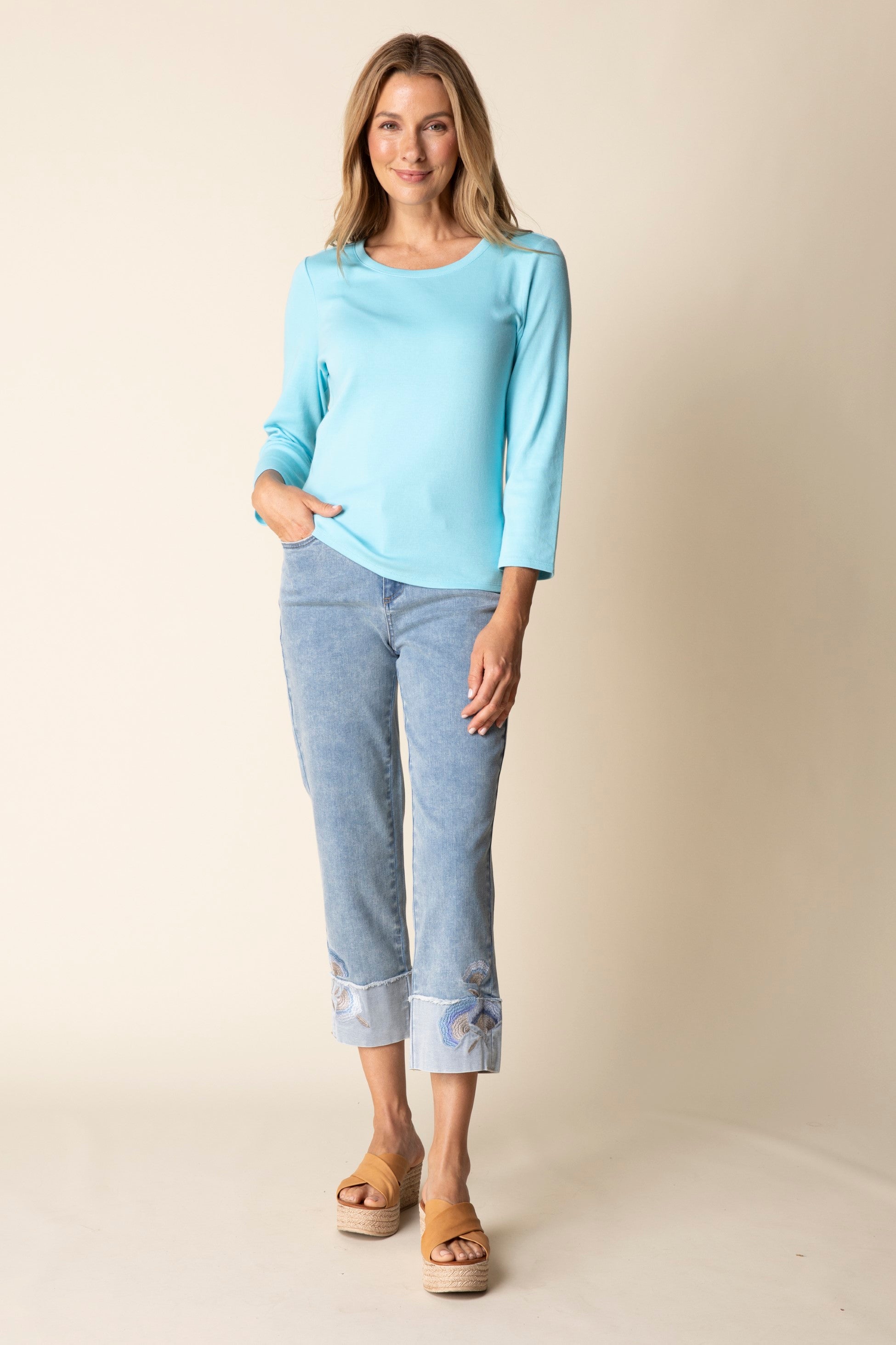 Woman wearing a light blue top and pants against a beige background