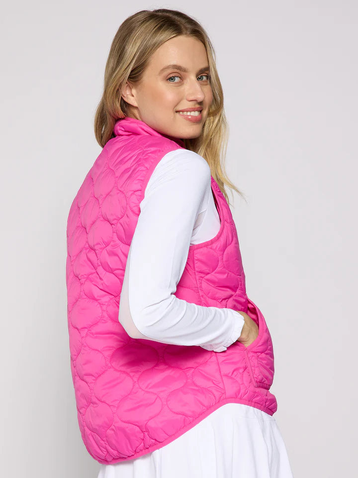 Woman wearing a pink quilted vest against a plain background