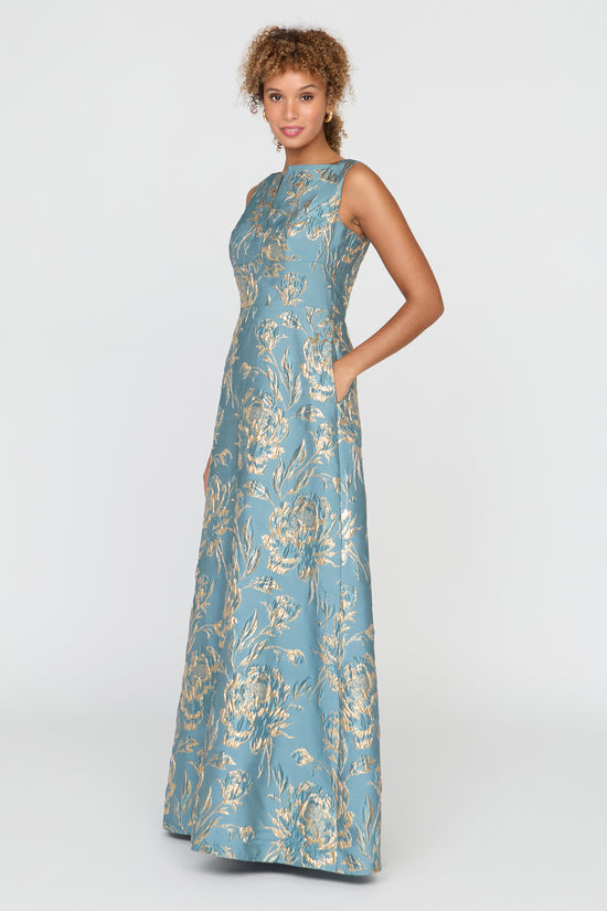 Woman wearing a blue floral evening gown on a white background