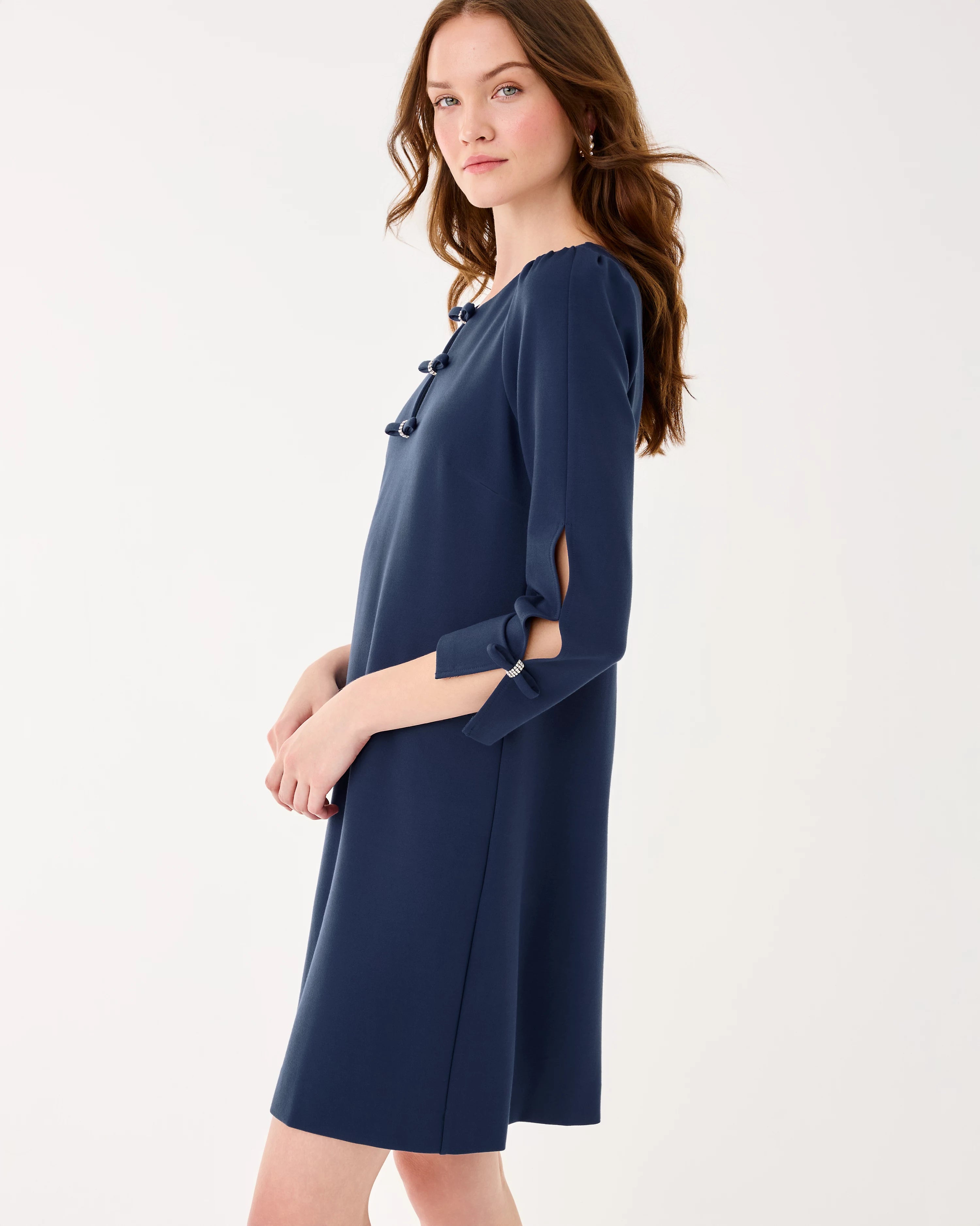 Woman wearing a navy blue dress with cut-out sleeves on a white background