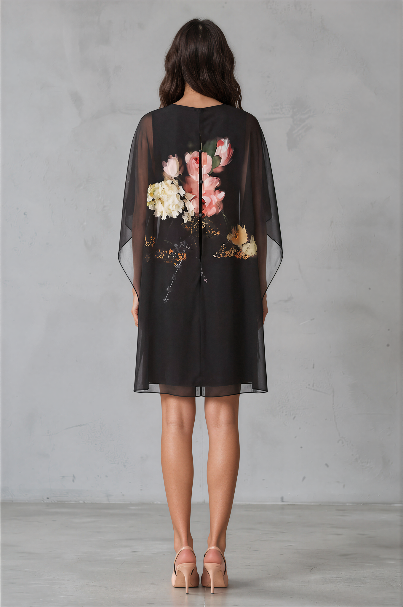 Woman models a black shaeer overlay dress with a large pink and white floral print on the front by Teri Jon Chiffon Print Caftan Overlay Dress