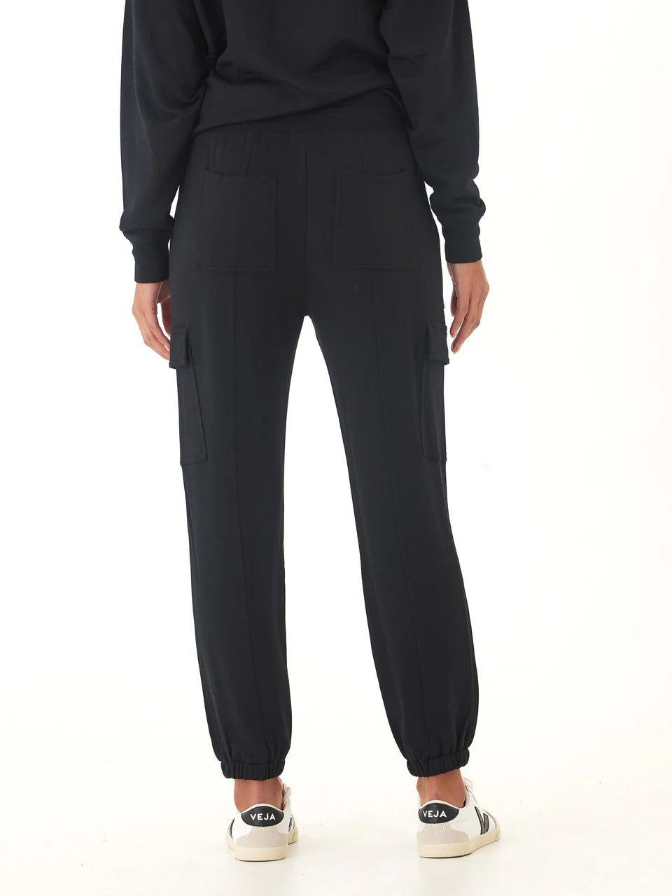 Person wearing black cargo jogger pants on a white background