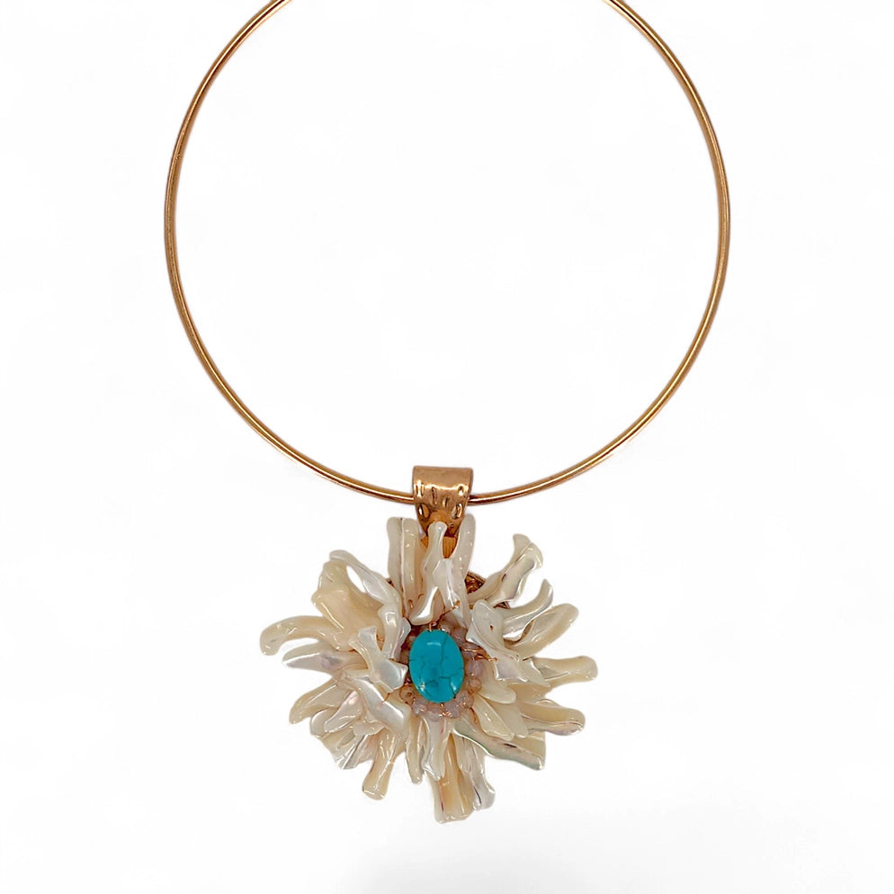 Gold necklace with a floral pendant featuring a blue gemstone on a white background