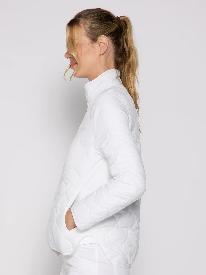 Woman wearing a white puffer jacket against a plain background