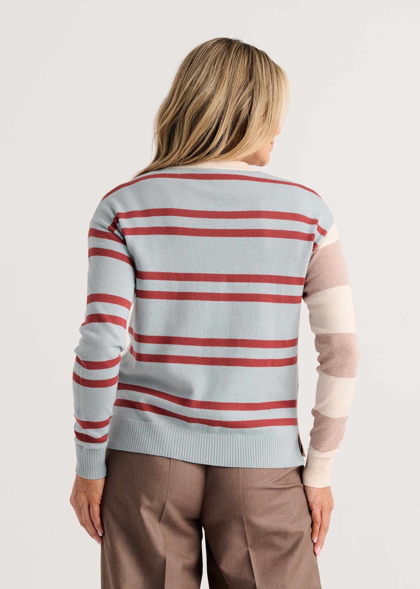 A woman viewed from the back wearing a light blue knit sweater with horizontal red and white stripes, plus beige color-blocked sleeves Zaket & Plover Bold Stripe Sweater Waxpaper