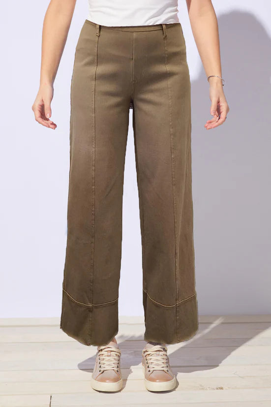 Person wearing brown, rust wide-leg jeans with a white background