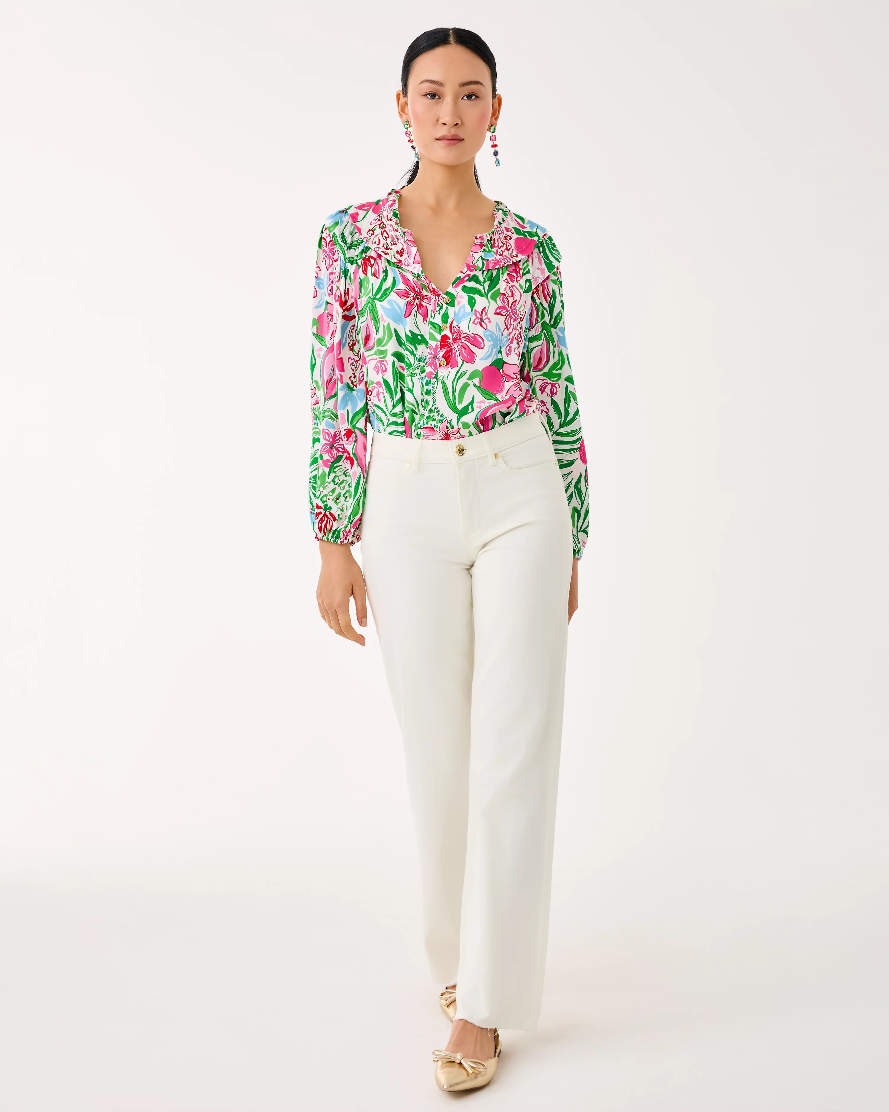Woman wearing a floral blouse and white pants on a white background