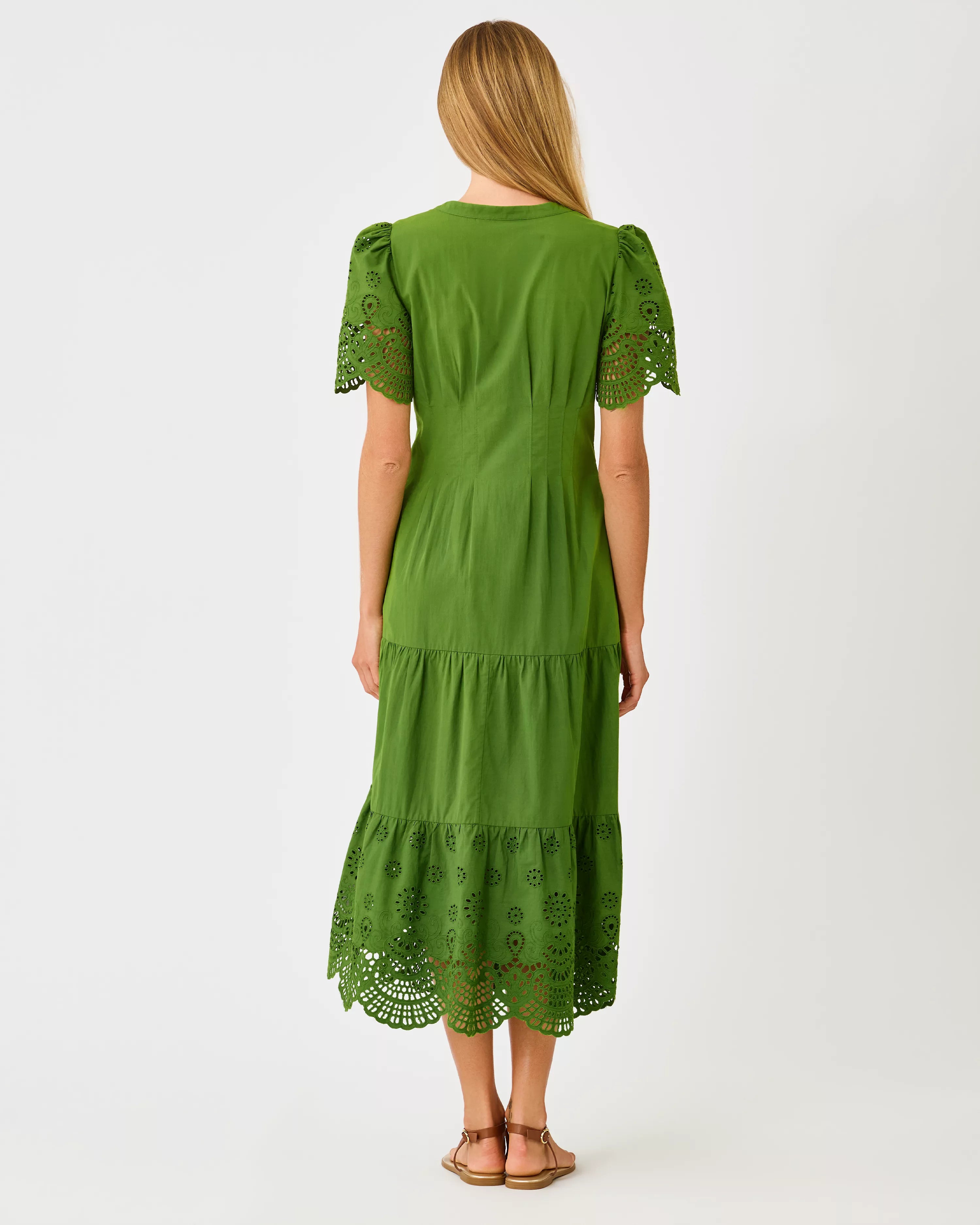 A woman modeling a green midi dress with short puff sleeves, a button-front neckline, and eyelet lace trim at the hem and sleeve cuffs lilly pulitzer wayland midi dress color Oregano Scalloped Eyelet Border Poplin