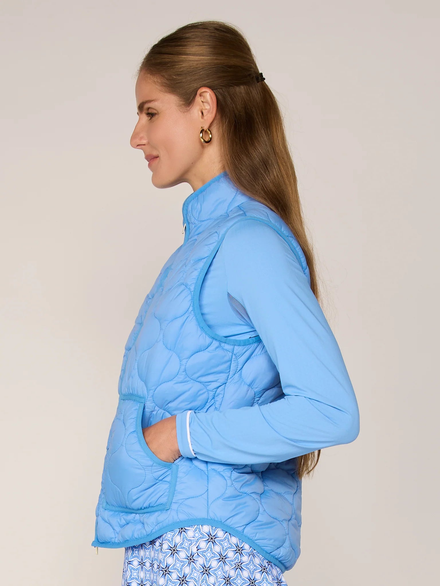 Woman wearing a light blue quilted jacket against a plain background