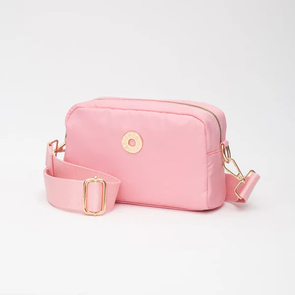 Pink crossbody bag with gold accents on a light gray background