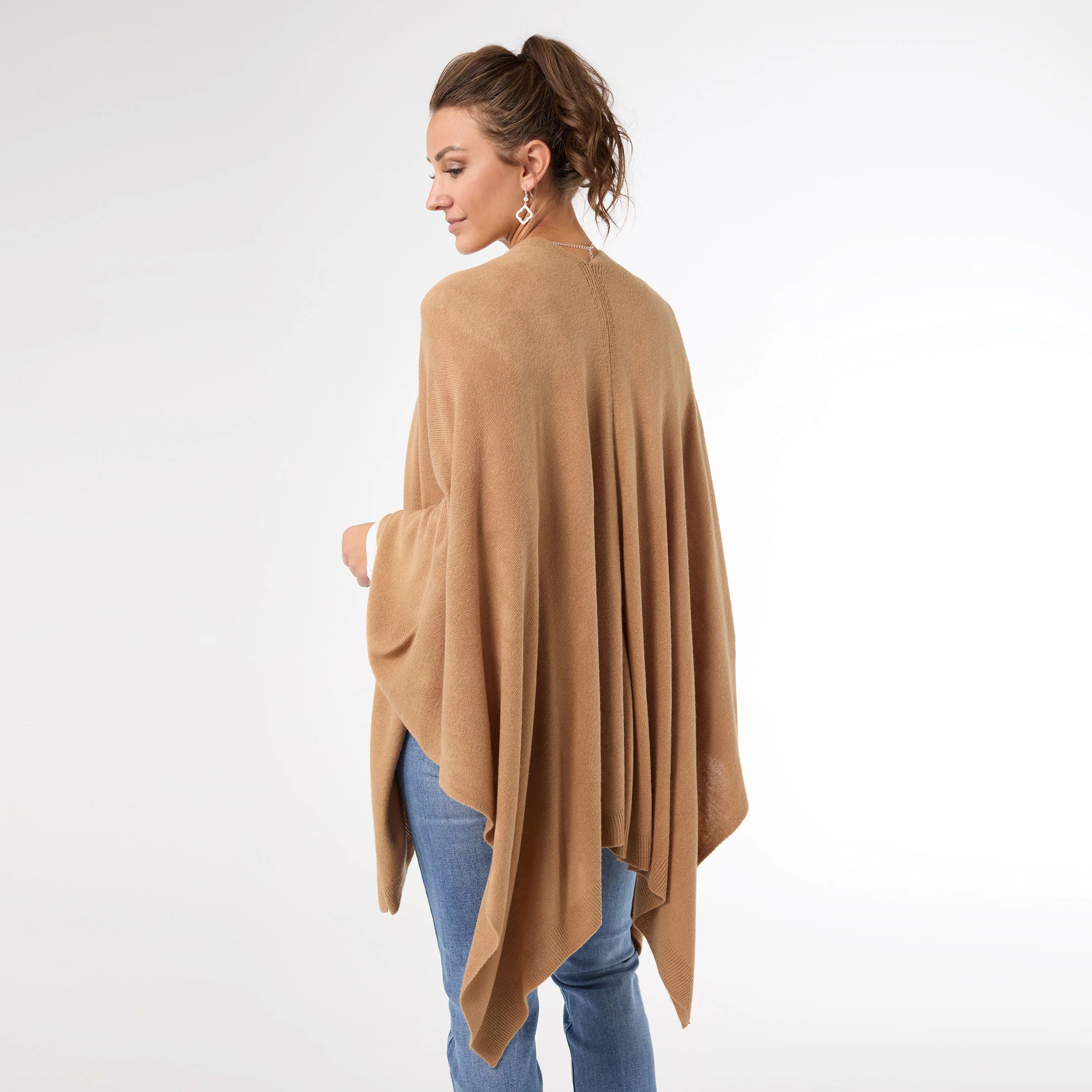 Woman wearing a beige poncho over a white background