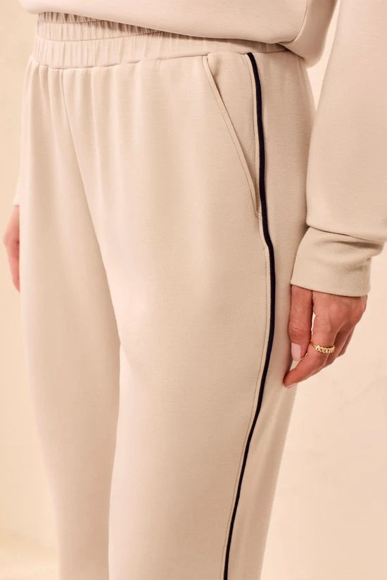 A woman modeling straight-leg pants, featuring thin black side stripes by tribal TECHNO LUX Jogger Pants With Contrast Piping And U-Hem