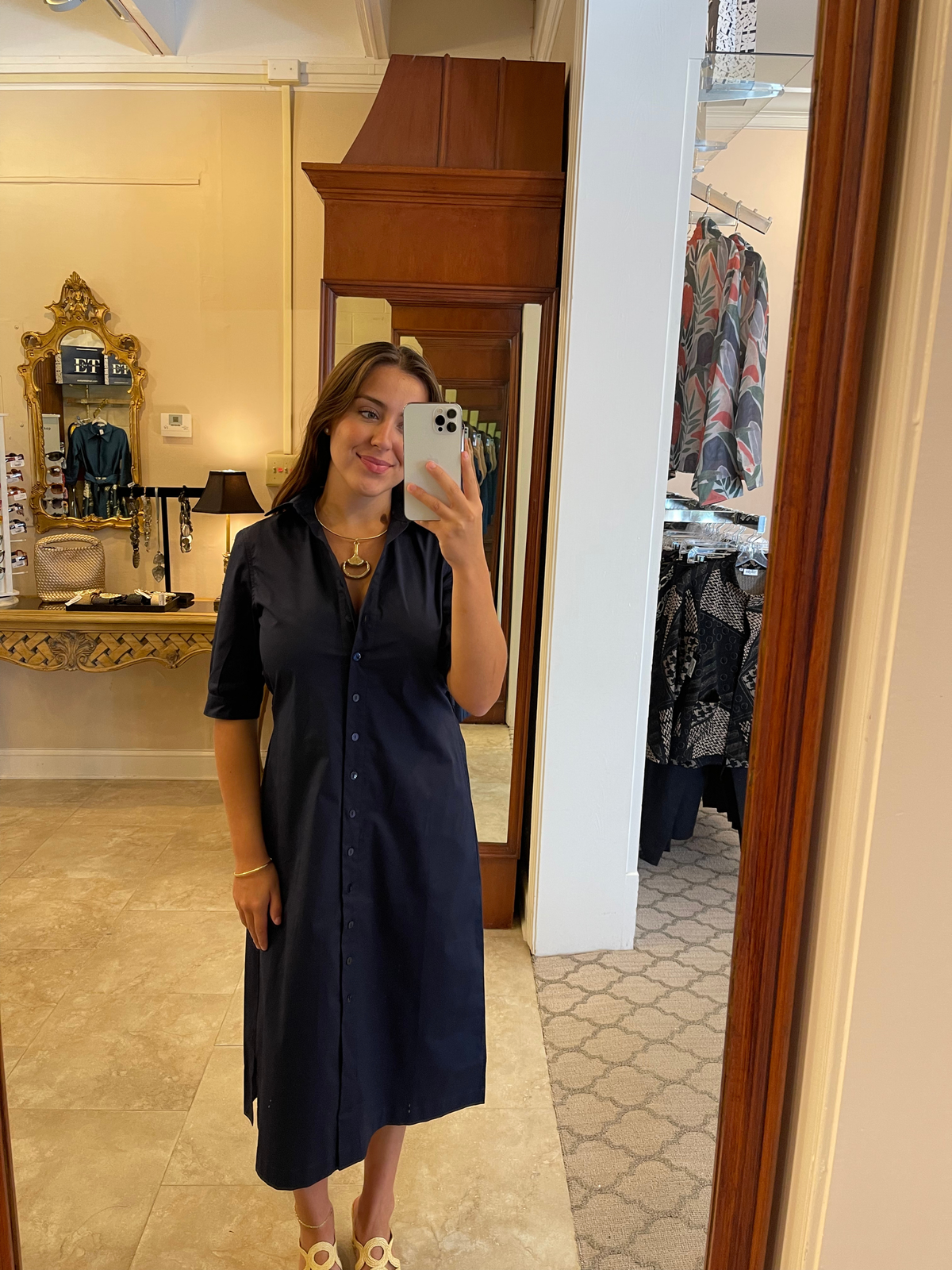 A woman modeling a dark navy midi shirt dress with short sleeves, a button-up front, and a matching self-tie belt.