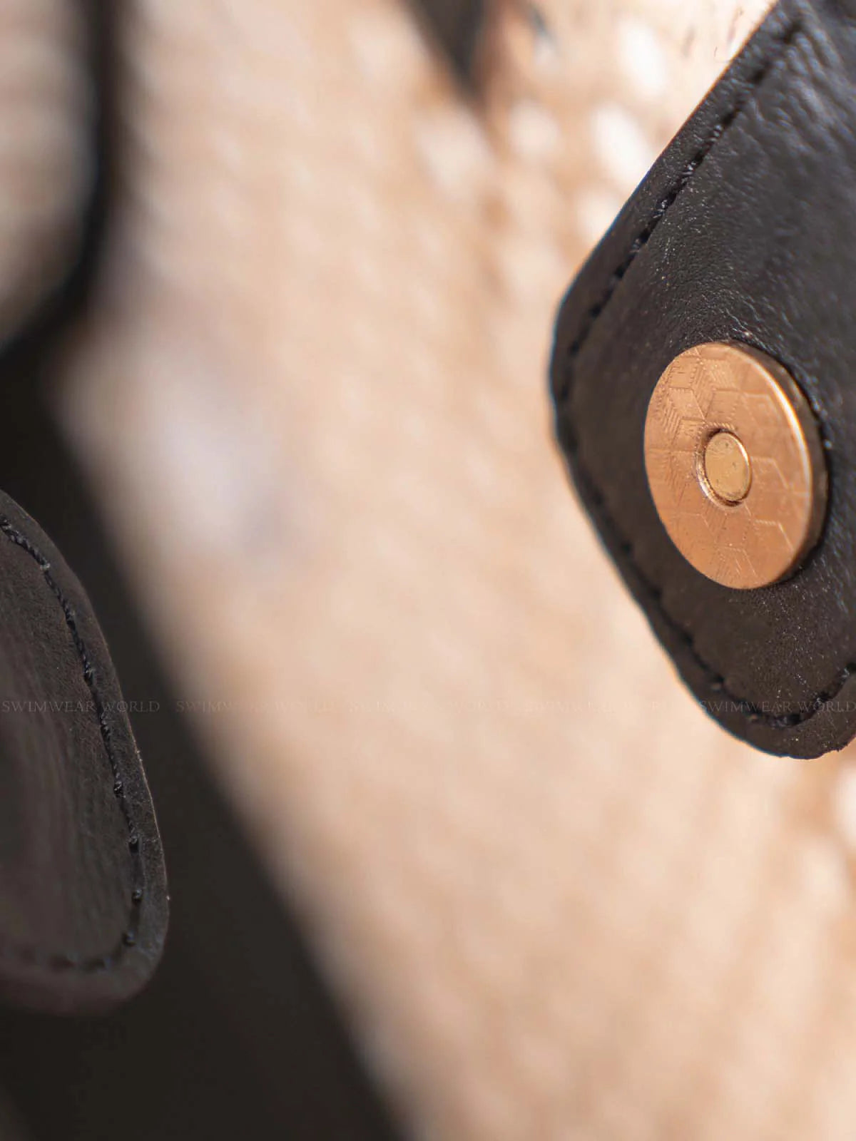 Close-up of a leather product with a button, likely a handbag or wallet.