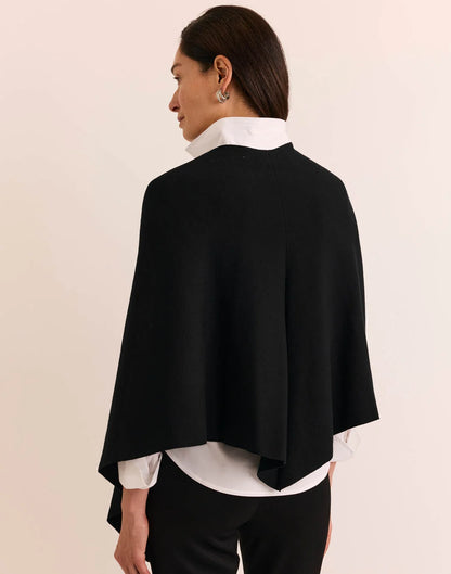 A woman modeling a black wrap shawl by  The H Edition Mabel Tab Fringe Wrap