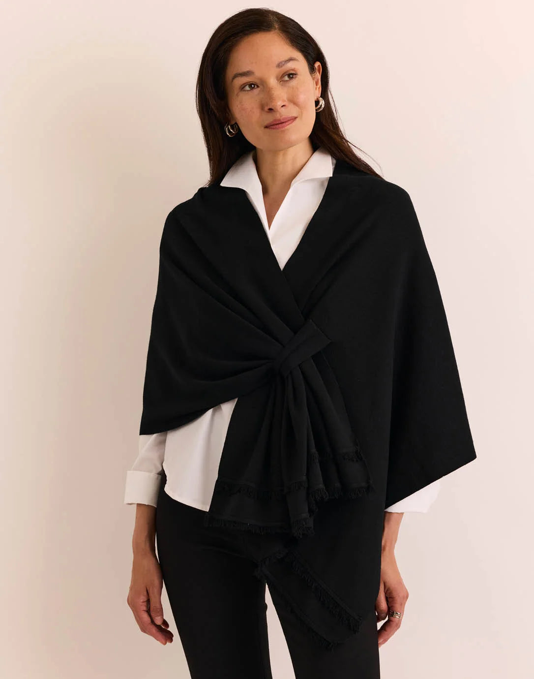 A woman modeling a black wrap shawl by  The H Edition Mabel Tab Fringe Wrap