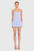 Woman wearing a light blue strapless dress with ruffled layers on a white background