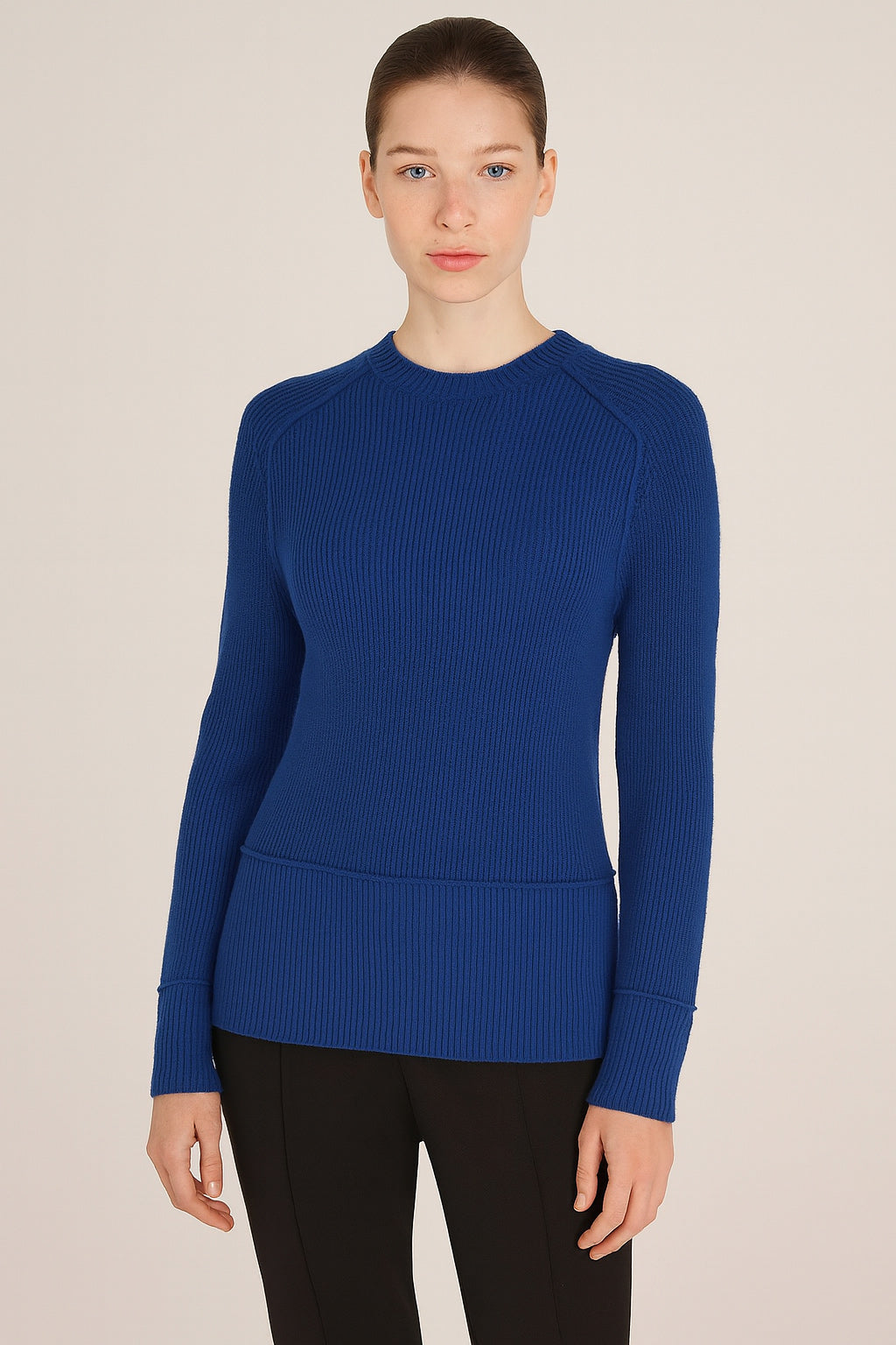 Woman wearing a blue ribbed sweater against a beige background
