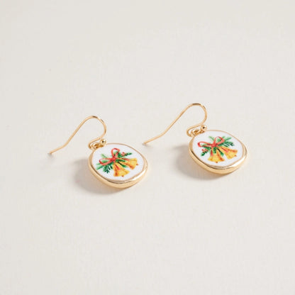 Gold earrings with circular designs featuring colorful Christmas bells bows on a light gray background