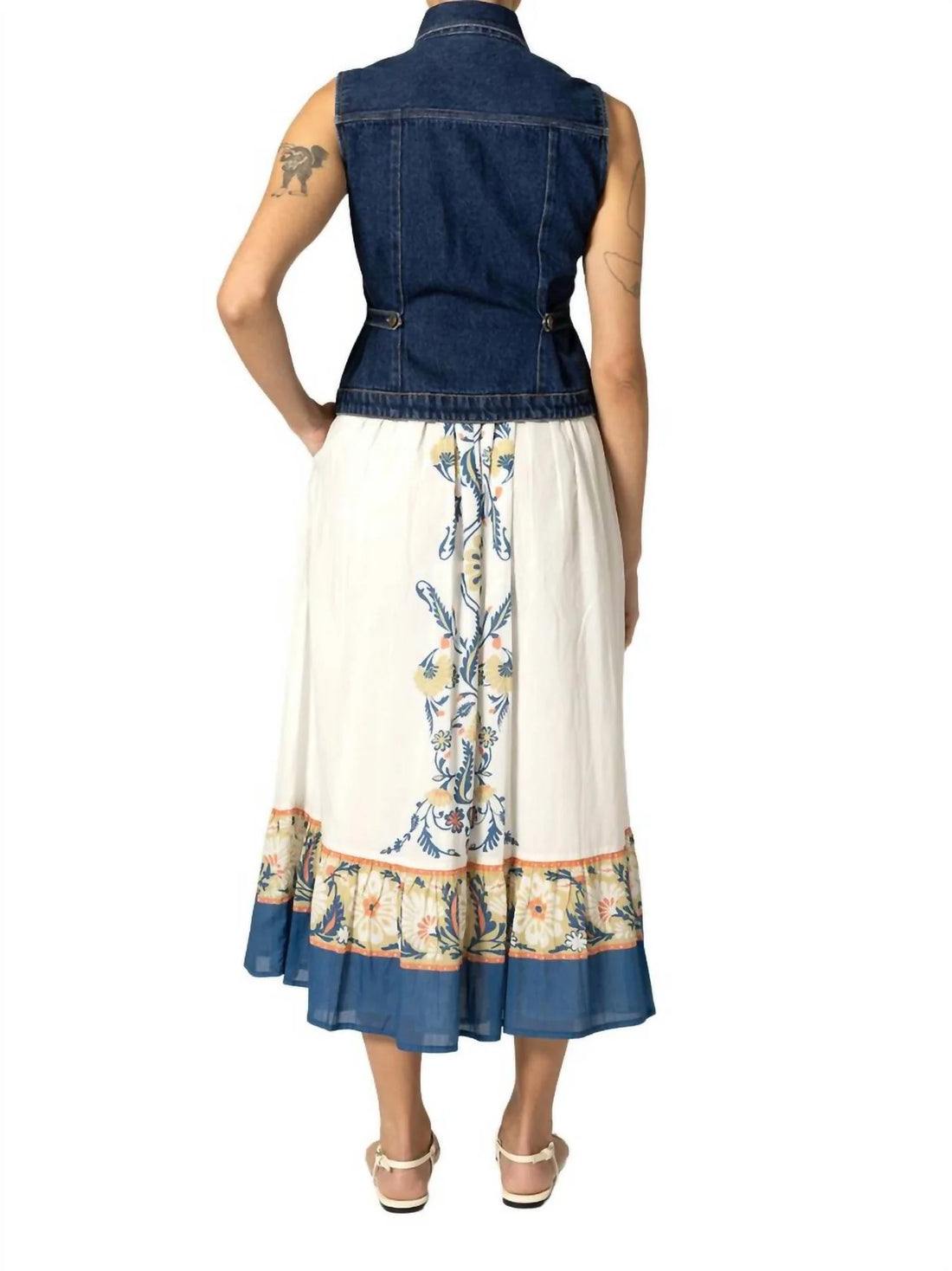 Woman wearing a denim vest over a floral dress on a white background