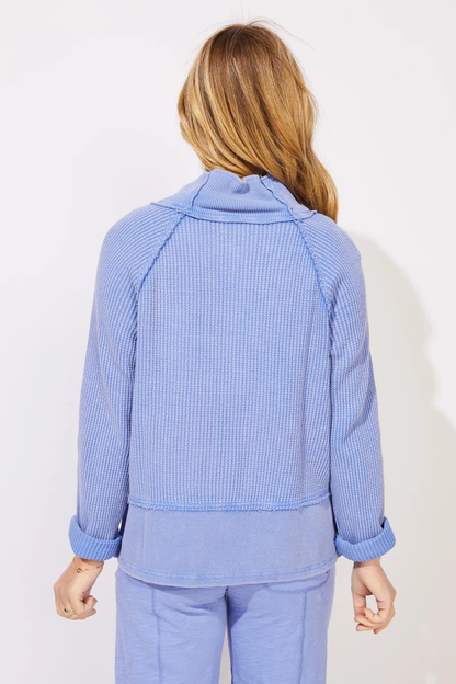 A woman modeling ESCAPE BY HABITAT  MIXED WAFFLE MOCK NECK - 97011 Baja Blue a light blue ribbed knit cardigan with a high stand collar and button-front closure