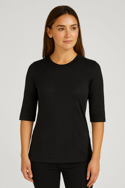 Woman wearing a black three-quarter sleeve shirt against a plain background