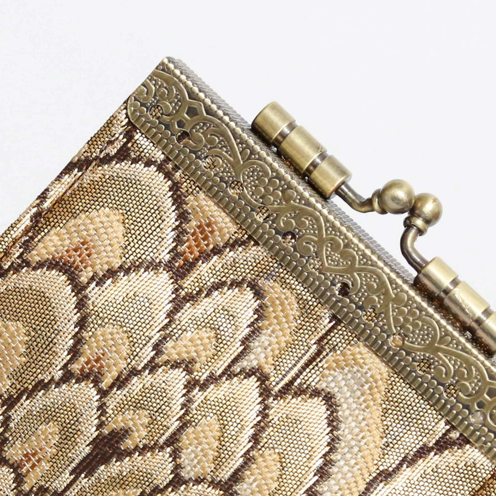 Close-up of a metallic clutch with intricate design and gold accents.