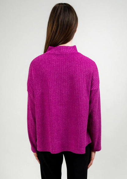 Back of a woman wearing a fuchsia sweater against a plain background