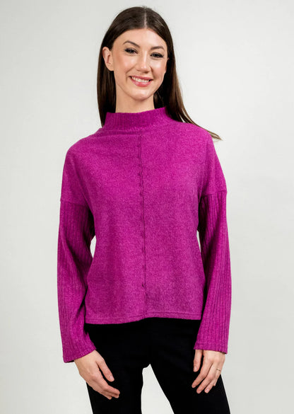 Woman wearing a fuchsia sweater against a plain background