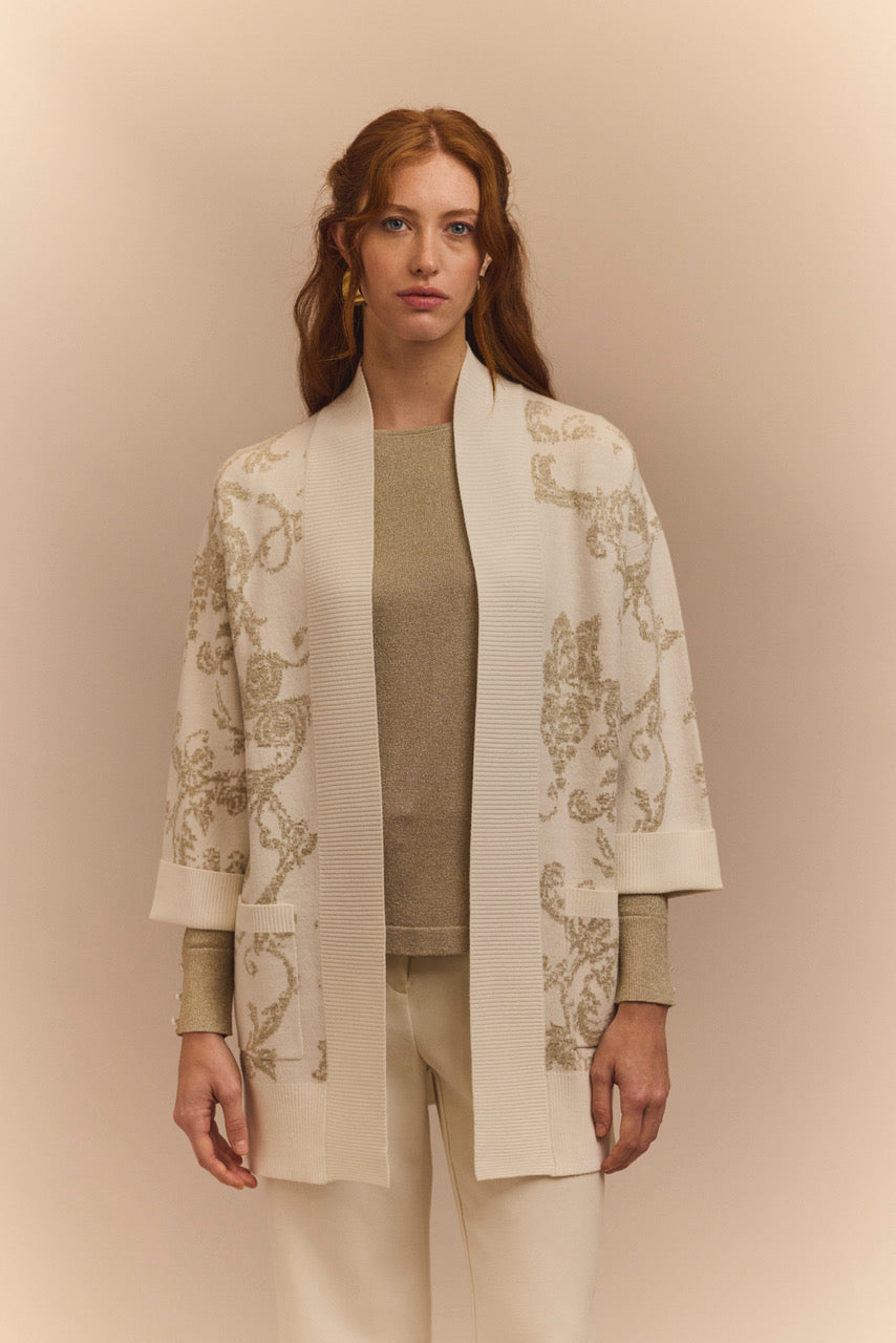 Woman wearing a stylish beige cardigan with floral patterns on a beige background