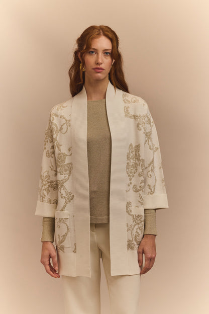 Woman wearing a stylish beige cardigan with floral patterns on a beige background