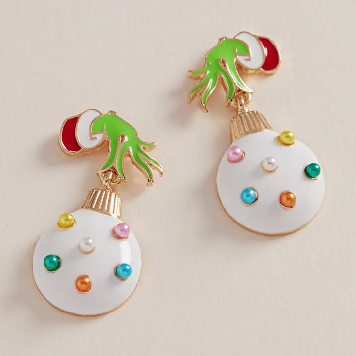 Colorful Christmas ornament earrings on a beige background