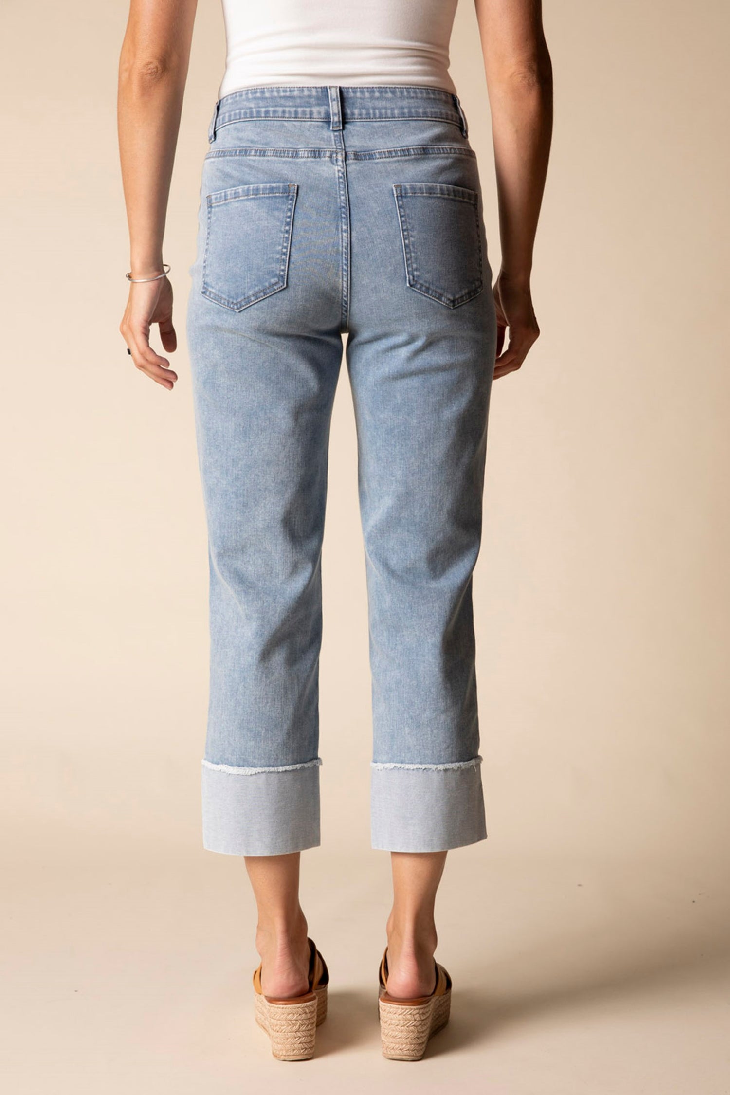 Light blue jeans worn by a person on a beige background