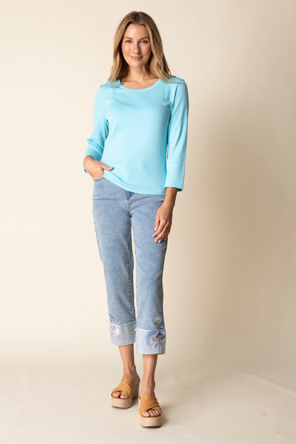 Woman wearing a light blue top and pants against a beige background