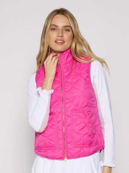 Woman wearing a bright pink quilted vest over a white shirt on a light gray background