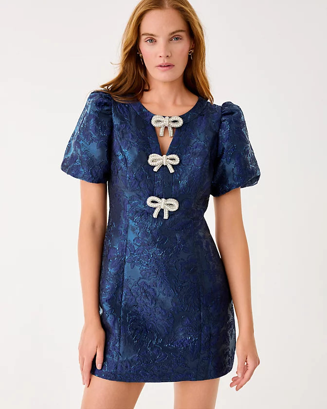 Woman wearing a blue dress with white bow details on a white background