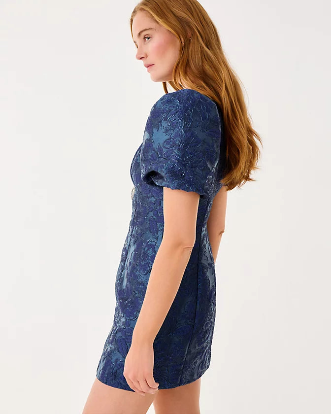 Woman wearing a blue patterned dress against a white background