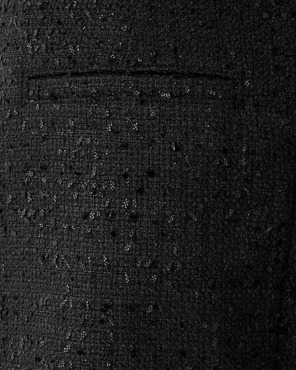 Close-up of a textured black fabric with a pocket detail