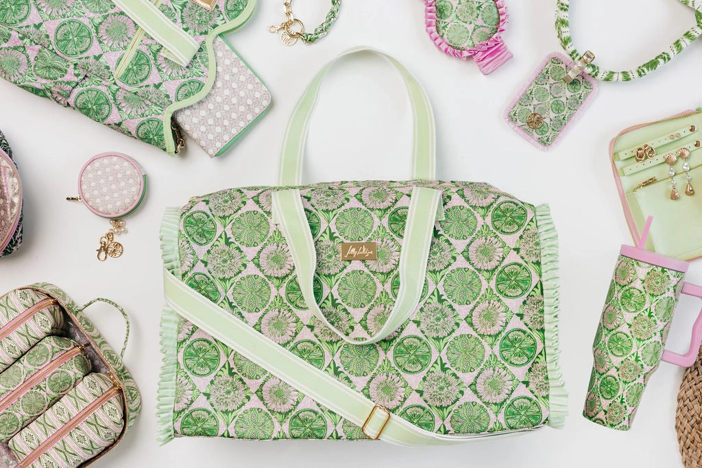 A Lilly Pulitzer Duffle Tote, Tropical Tiles tote bag with a green and pink citrus slice pattern, featuring pale green handles and a small gold-tone Lilly Pulitzer logo plaque. 
