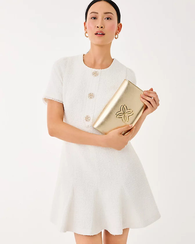 Woman in a white dress holding a gold clutch against a white background