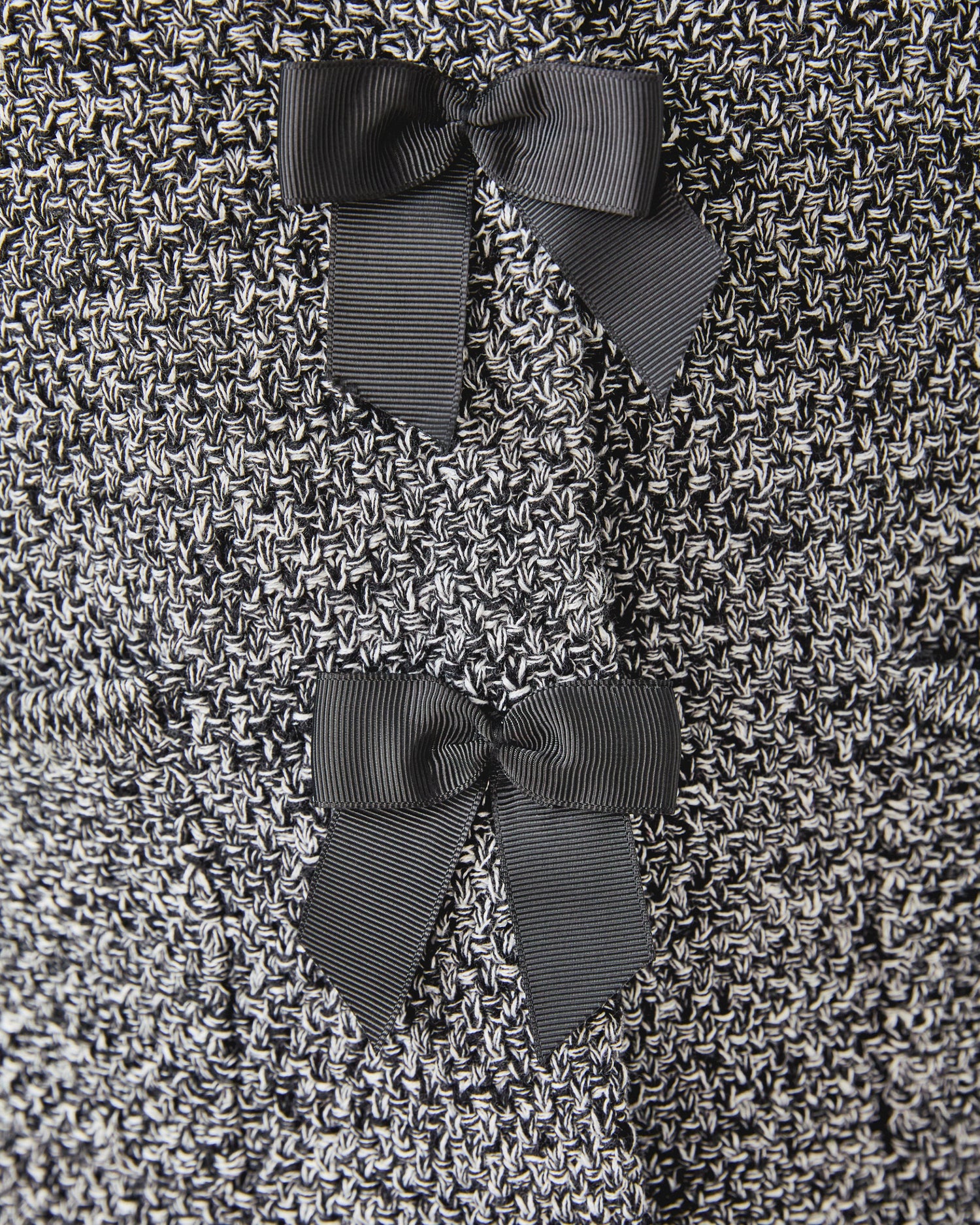Close-up of a textured fabric with three dark gray bows.