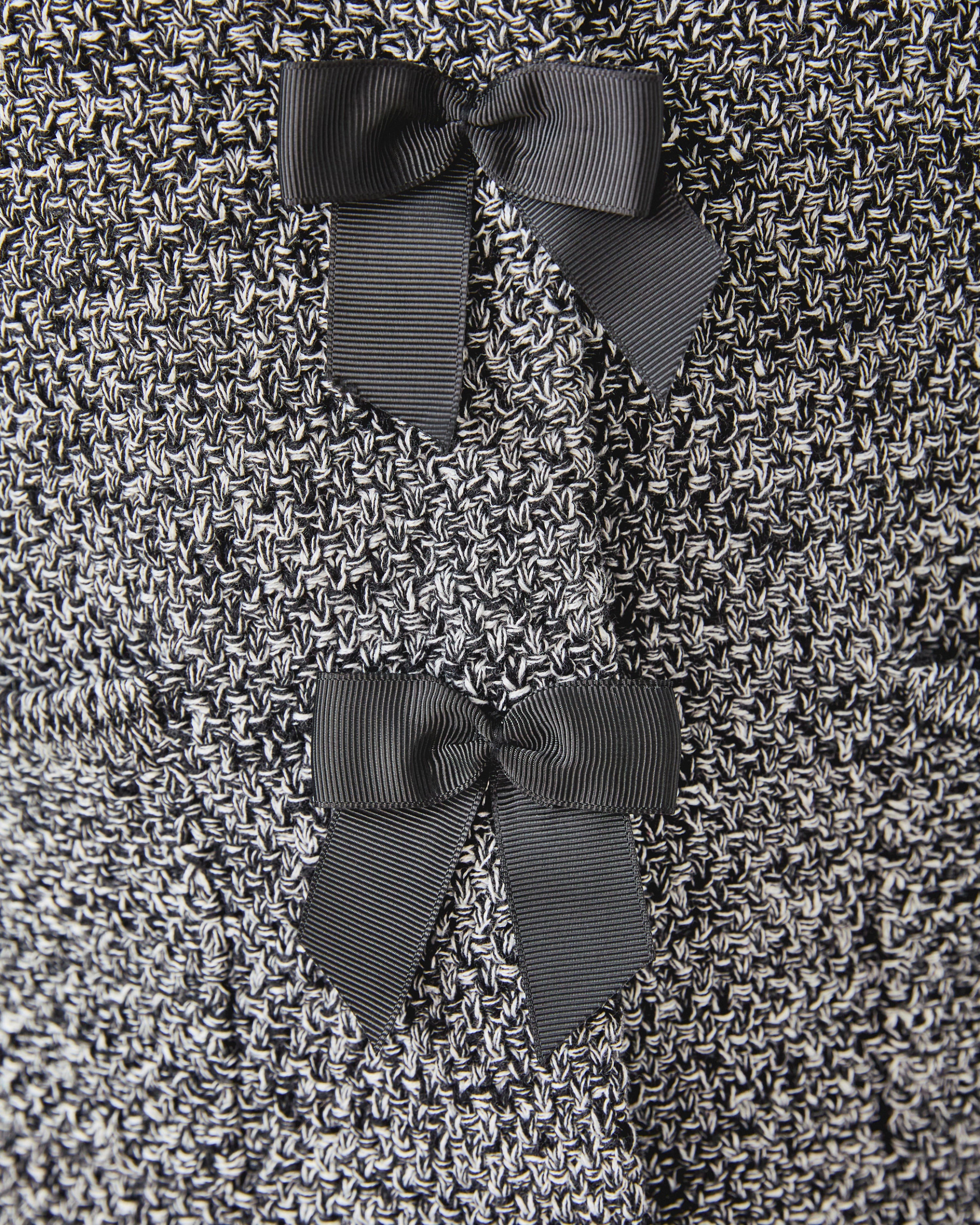 Close-up of a textured fabric with three dark gray bows.