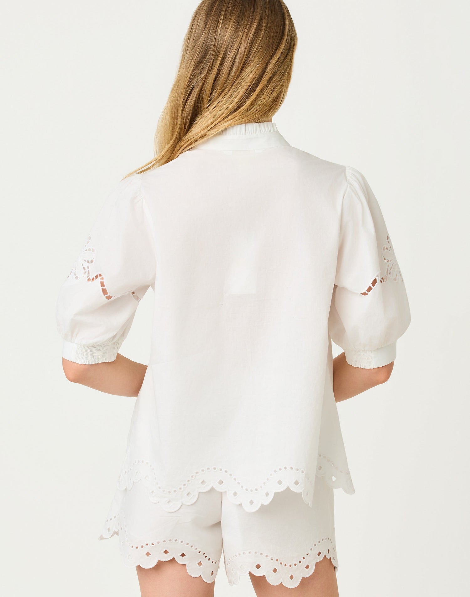 White outfit with lace details on a plain background