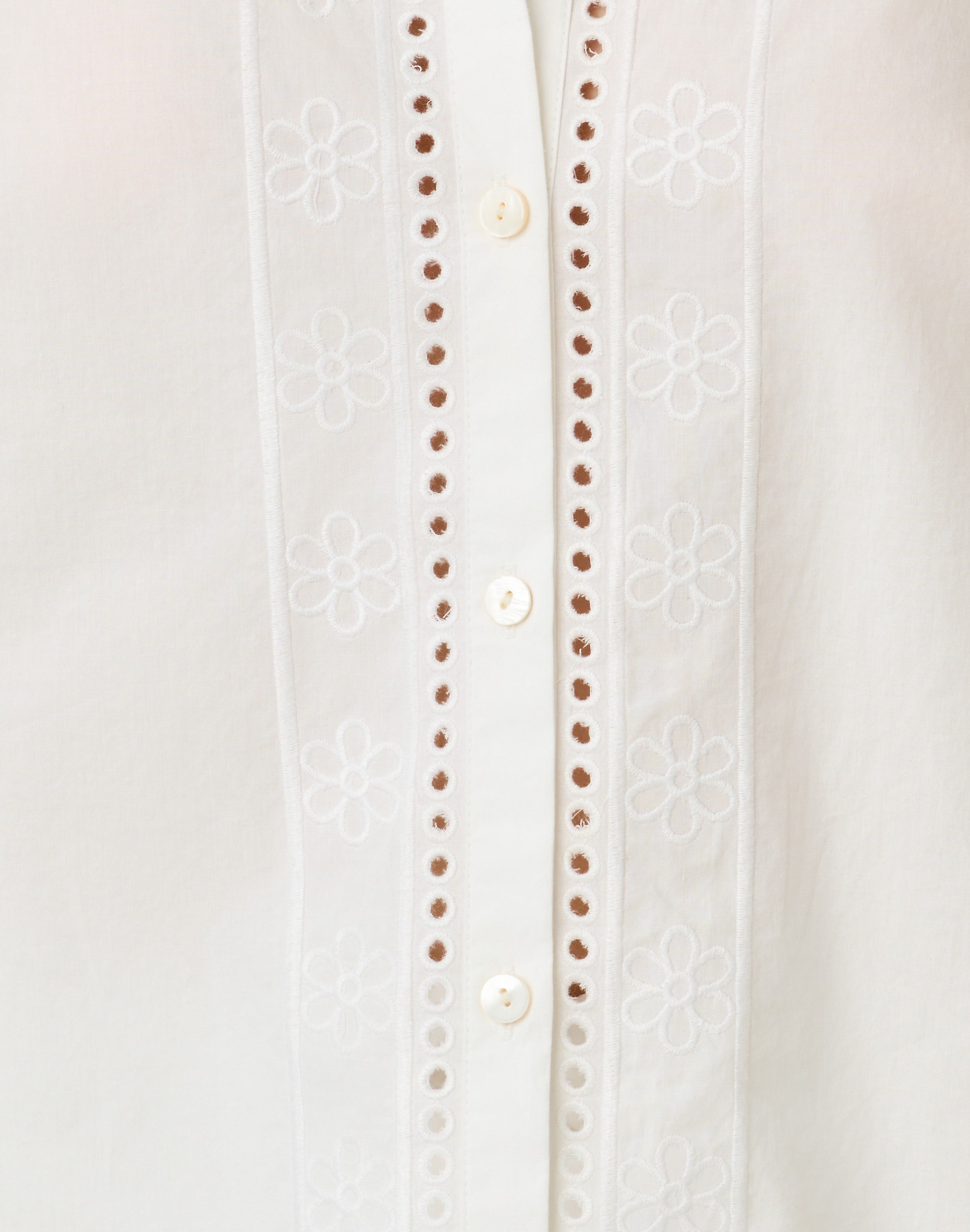 Close-up of a white blouse with button details on a light gray background