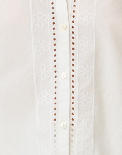 Close-up of a white blouse with button details on a light gray background